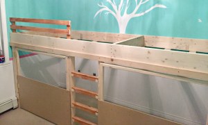 Instead of having the doors be solid plywood and then cutting out windows, it was going to be far cheaper to make half-doors out of half-sheets of plywood and leave the top of the doors open — framed with 2x2s. We put casters on the bottom of the doors so they’d slide more easily and not put too much weight on the hinges. We designed the swinging doors to be exactly the same size, to make things easier, and left enough room in the centre for the ladder. Typically, a bunk bed ladder leans out into the room so you can climb on a comfortable angle. But our kids have been climbers since they were babies so we knew we wanted to build a somewhat challenging ladder: straight up and down. (The bonus was that it wouldn’t take up any more floor space, because the bed was looking more and more gargantuan as we worked.) The final step of construction was adding a simple safety rail near the top of the mattress so our daughter wouldn’t tumble out of bed at night — it would be a seriously long, hard fall. We kept the bottom of the bed open, since that’s where it met with the ladder, and decided not to put a rail around the play area. Since there’s no mattress there, the kids have somewhat of a natural ledge to keep them in. While the construction was pretty easy, it was priming and painting that monster that took most of the effort. As much as I really, really didn’t want to have to prime it, the associate at Kent gently convinced me that it was the best way to make sure the paint wouldn’t chip or flake. And so I primed . . . and primed . . . and primed. We chose a soft grey for the bed colour (PPG’s Rice Chips) to go with the new blush-coloured walls (PPG’s Pinot Noir), and we used SICO Furniture & Cabinet paint to ensure we’d get a durable finish. For a finishing touch, I nailed some thick trim on the doors and painted some of the trimwork a glossy un-tinted white. I traced a small dessert plate again and again on a sheet of MDF and my husband cut them out with his scroll saw to create the cutest scallop detail. I also added a shiny white metal mailbox, a vintage lock plate from Phillips & Chestnut Victorian Salvage and Decor, and house numbers sprayed gold inside a white oval frame. I hung cafe curtain rods inside each of the doors and used gold metal clips to hang homemade curtains in a beautiful deep rose. It really looks like a sweet little playhouse under there. For the elevated play area, I just covered the MDF ‘floor’ with some pink cotton fabric and stapled it tightly underneath — rather than painting the MDF and worrying about it getting scratched up underfoot. With a few throw pillows and rattan storage bins, it’s the perfect spot for our daughter’s Shopkins collection and other small toys. She loves playing up there, and the best part is that I don’t care how messy it gets because you can’t see it! Even though our daughter’s new loft bed is massive, it doesn’t feel like it takes up the entire room because it’s so multi-functional. The rest of her room is empty — except for the coral bookcase built from end tables that I showed you a few weeks ago — so there’s plenty of breathing room. What started off as an idea for a simple loft bed turned into something much more involved, but I’m so happy with how it turned out. By thinking vertically, we were able to double the available play-space while also hiding the toy clutter. I swear, her bedroom has NEVER stayed this clean — or looked this beautiful.